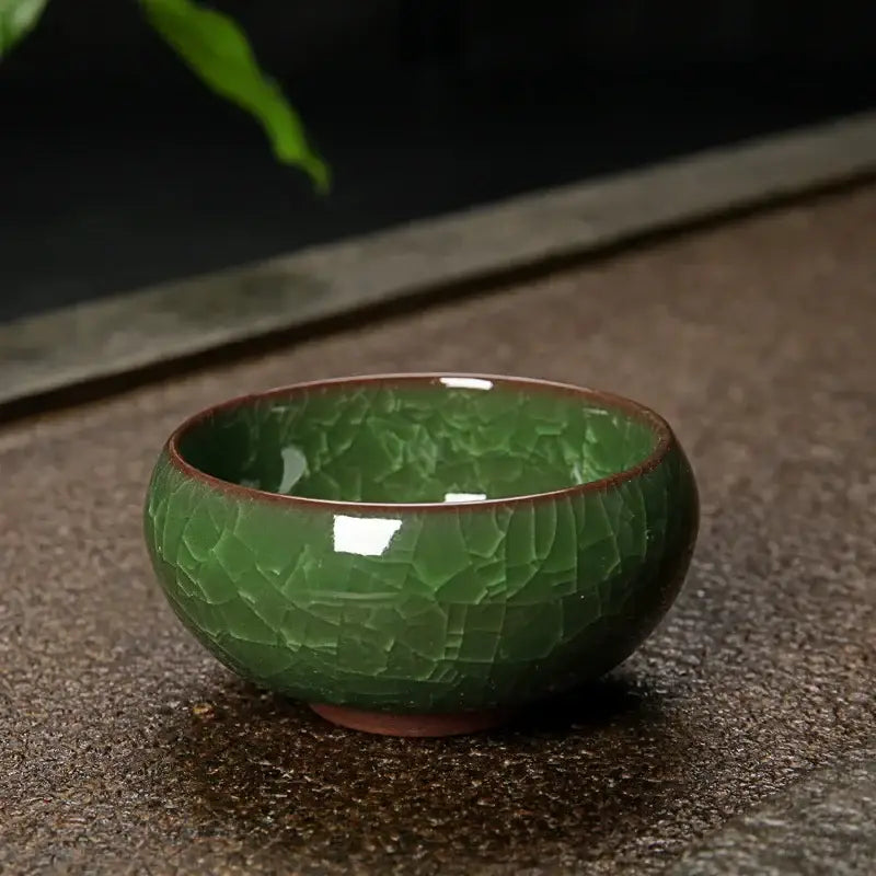 A glossy jade-green ice cracking ceramic tea bowl with crackled glaze and brown rim for decorbites ice cracking decor