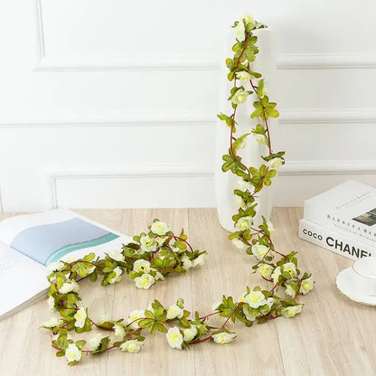 A delicate flowers vine garland featuring cream-colored rose flowers and green leaves on thin stems for decor