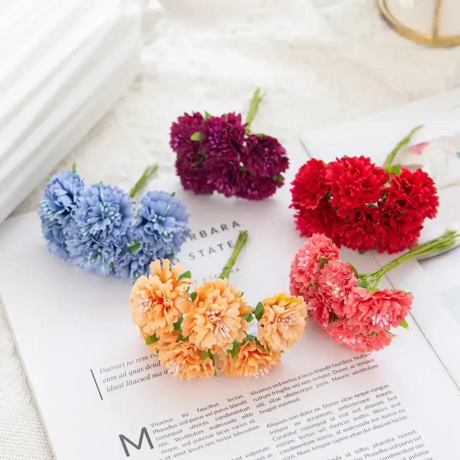 A cluster of vibrant multicolor silk carnation stamen flowers arranged on a printed page for living room decorbites decor