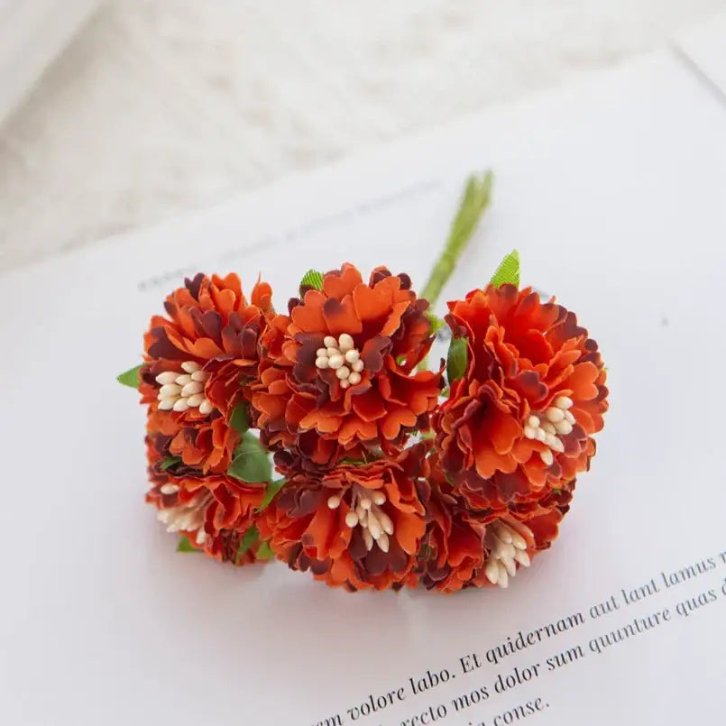 A cluster of vibrant orange and maroon decorbites carnation stamen silk flowers with white centers for living room decor