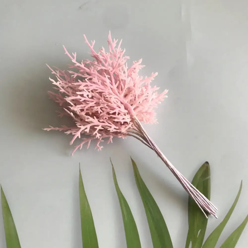A delicate pink artificial dried flower bouquet with slender stems in a white vase for living room decor