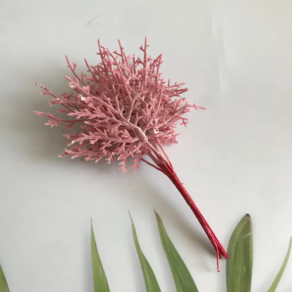 A delicate pink artificial dried flower bouquet with frosty texture and bundled red stems in a white vase for living room