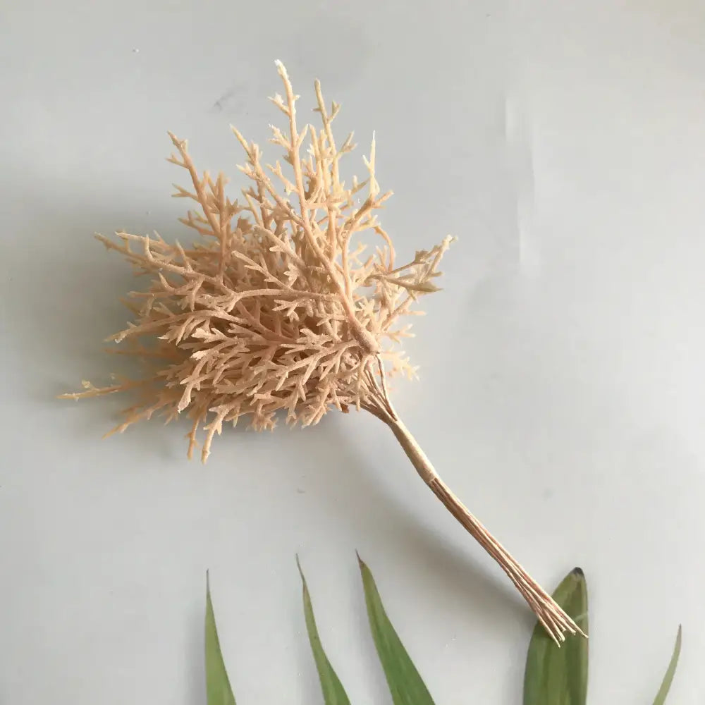 Beige intricately branched artificial coral piece with slender stem complementing dried flower bouquets in white vase living room
