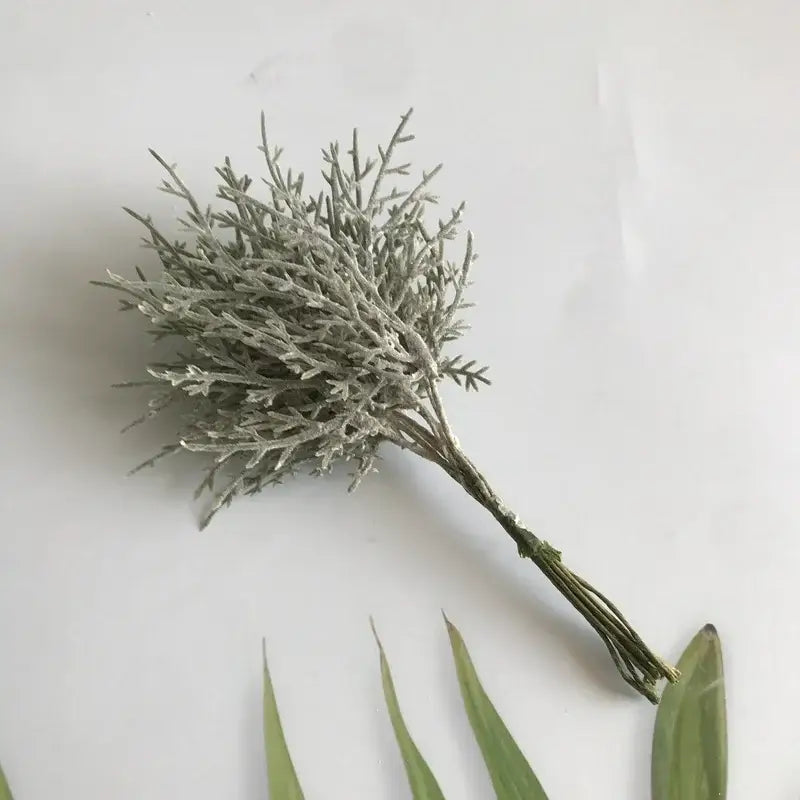A delicate frosted silver artificial dried flower bouquet with fine twig-like branches in a white vase for living room