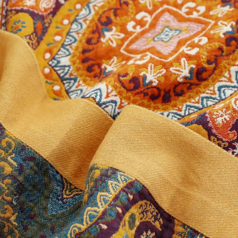 Vibrant orange and gold paisley patterned nordic throw blanket made of textured mustard-yellow fabric for bedroom use