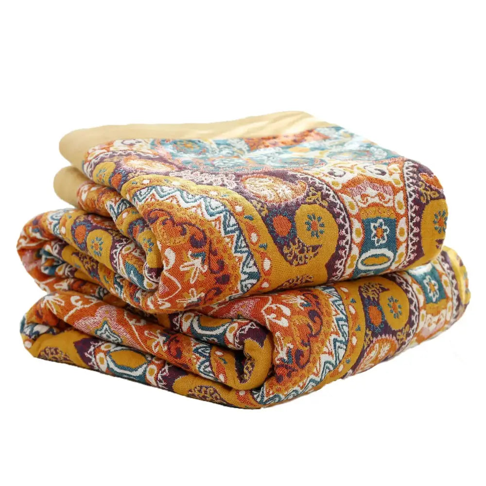 Folded warm-toned nordic throw blanket with vibrant orange gold paisley pattern perfect for bedroom bedspread use