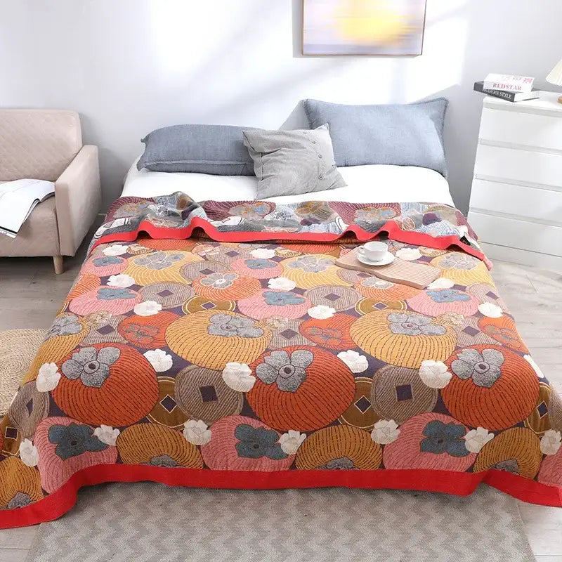 A cozy nordic throw blanket featuring a vibrant embroidered pattern of orange and pink pumpkins with floral accents