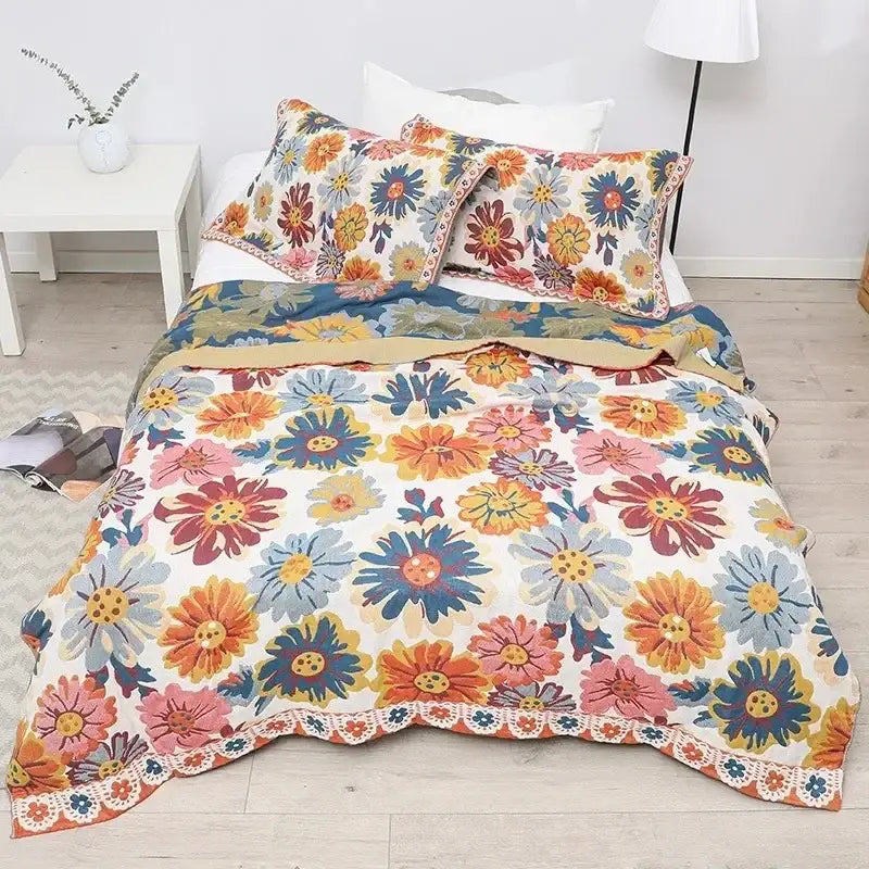 Vibrant nordic throw blanket featuring orange gold geometric and colorful daisy floral patterns with lace trim on cream background