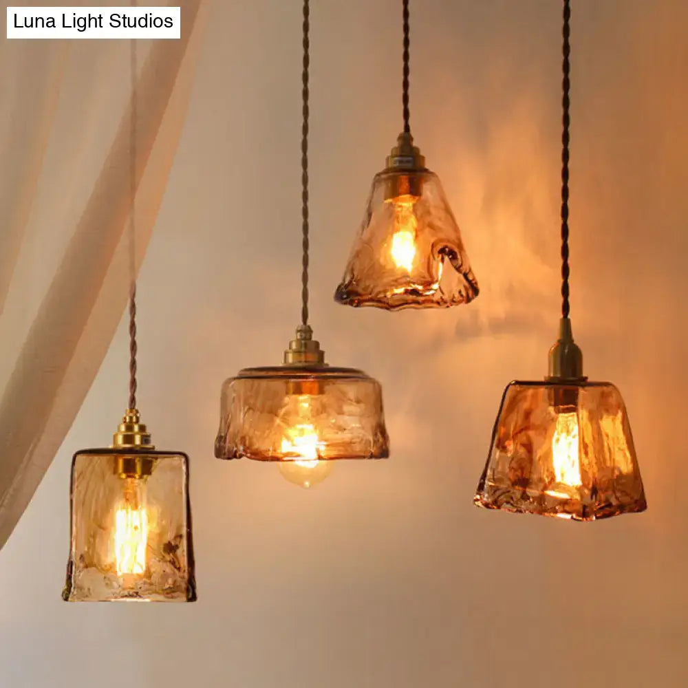 Three amber alabaster glass pendant lamps with brass accents hang from twisted cords for living room lighting