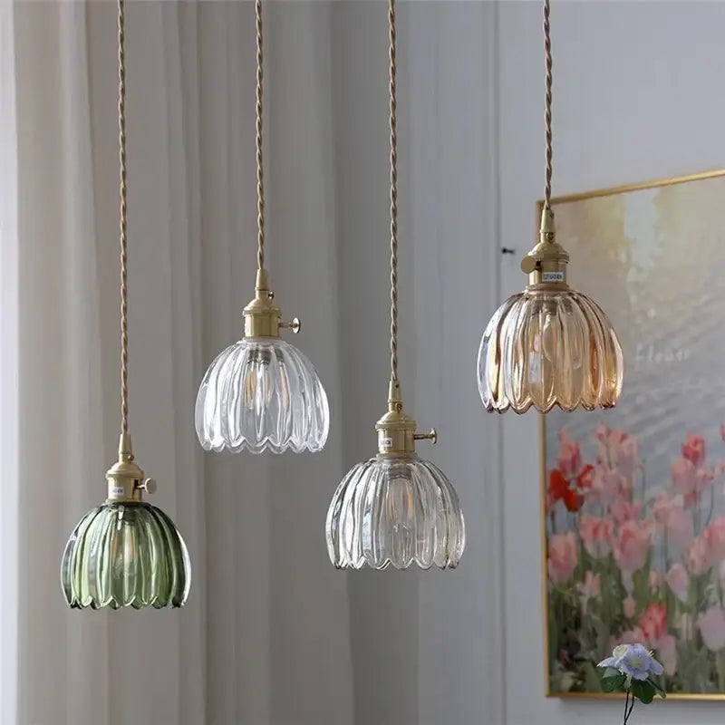 Four elegant vintage amber and clear glass pendant lights with ribbed shades and iron finish, suspended by twisted brass cords