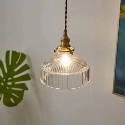 Vintage amber colored glass pendant light with vertical ridges featuring clear ribbed glass and brass fixture