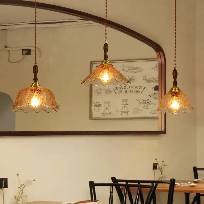 Three amber cracked glass led pendant lights with scalloped edges and brass accents for vintage kitchen decorbites