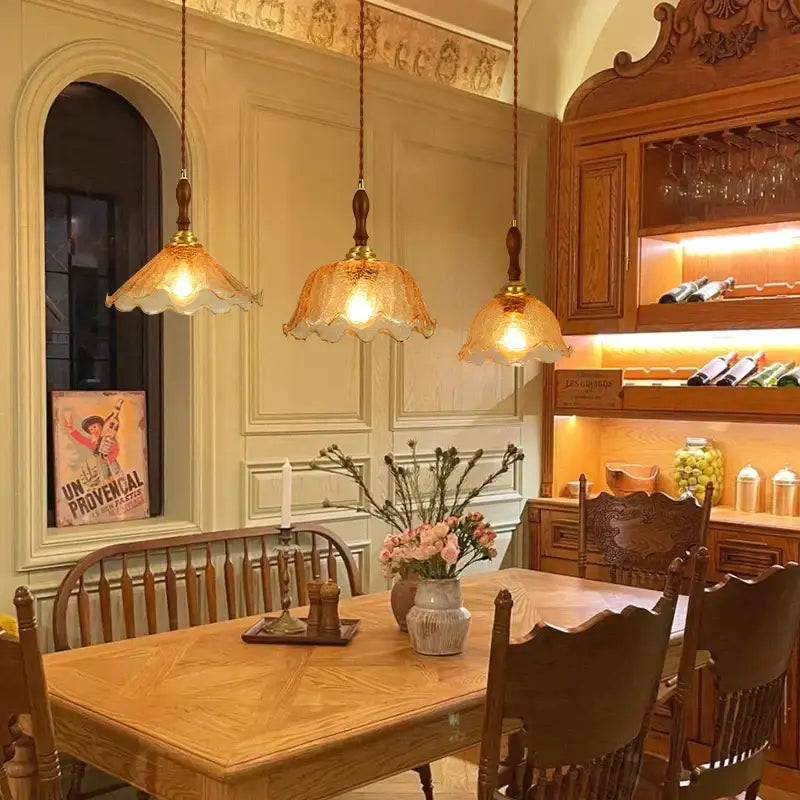 Three warm-toned vintage amber cracked glass led pendant lights with brass accents above wooden dining table decorbites