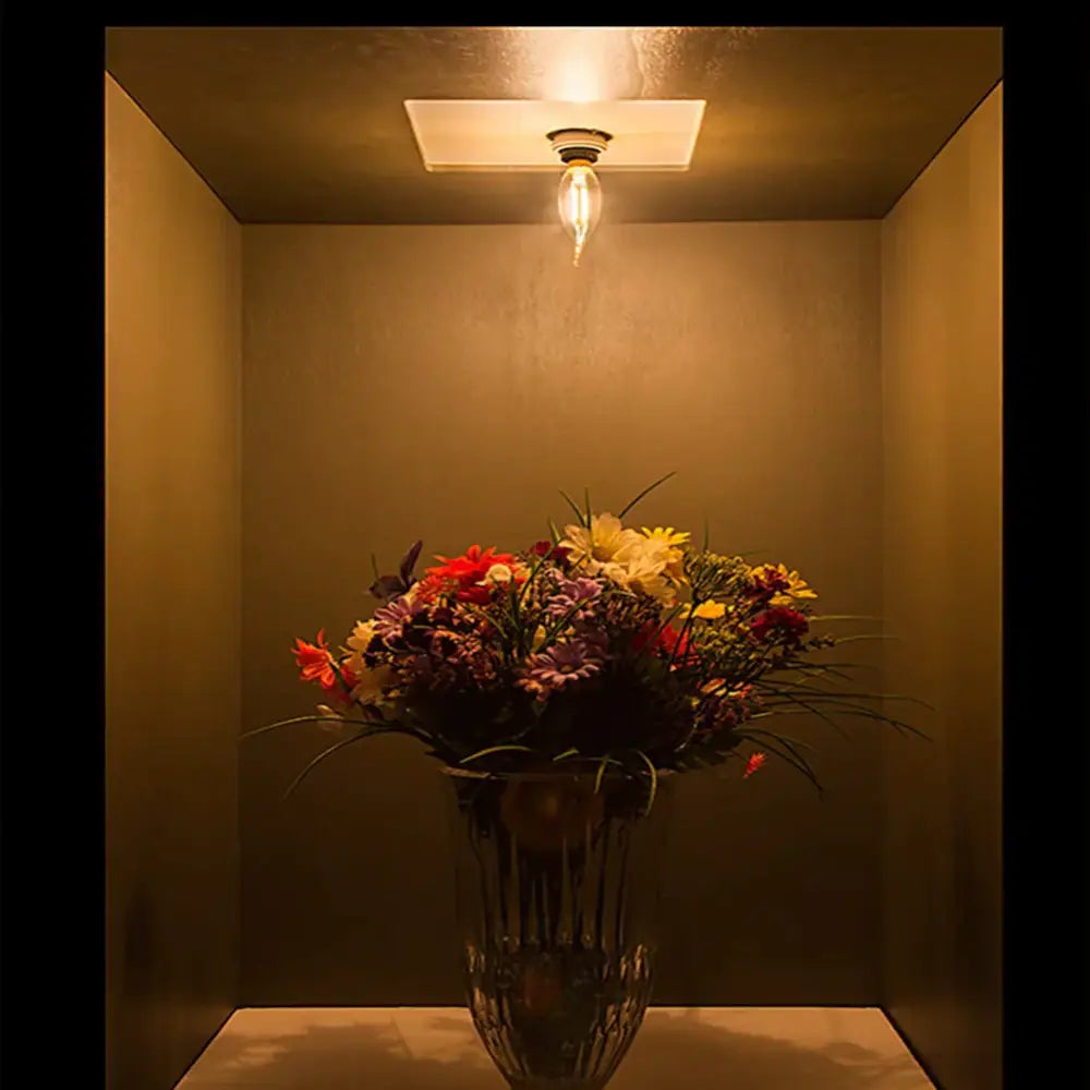 A vibrant mixed-bloom floral arrangement in a crystal vase complements the vintage amber dimmable led filament dining pendant light