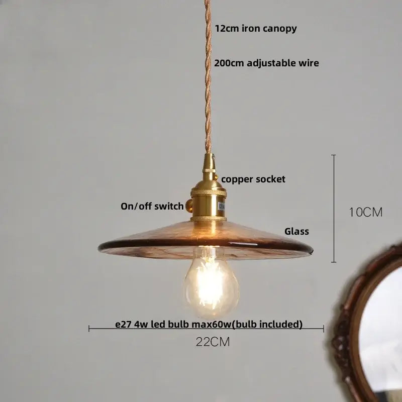 A warm-toned vintage amber glass adjustable pendant light with brass-finished copper socket for dining room use