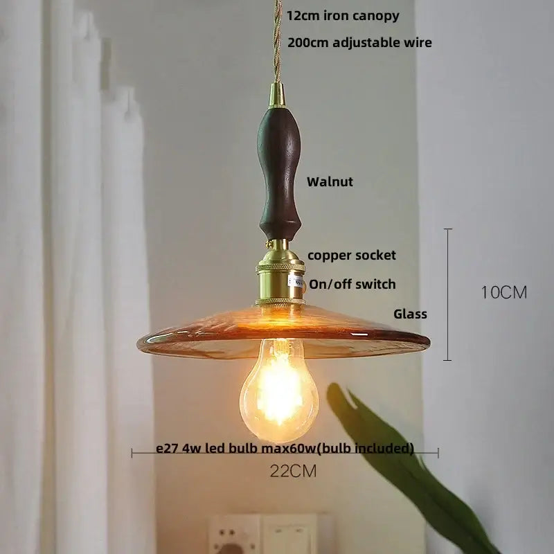 A vintage amber glass adjustable pendant light with dark walnut iron canopy and brass hardware for dining room use