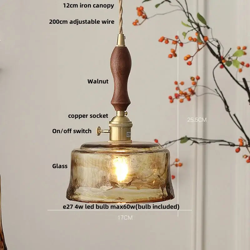 A warm amber glass adjustable led pendant light with walnut wood handle and brass accents for dining room use