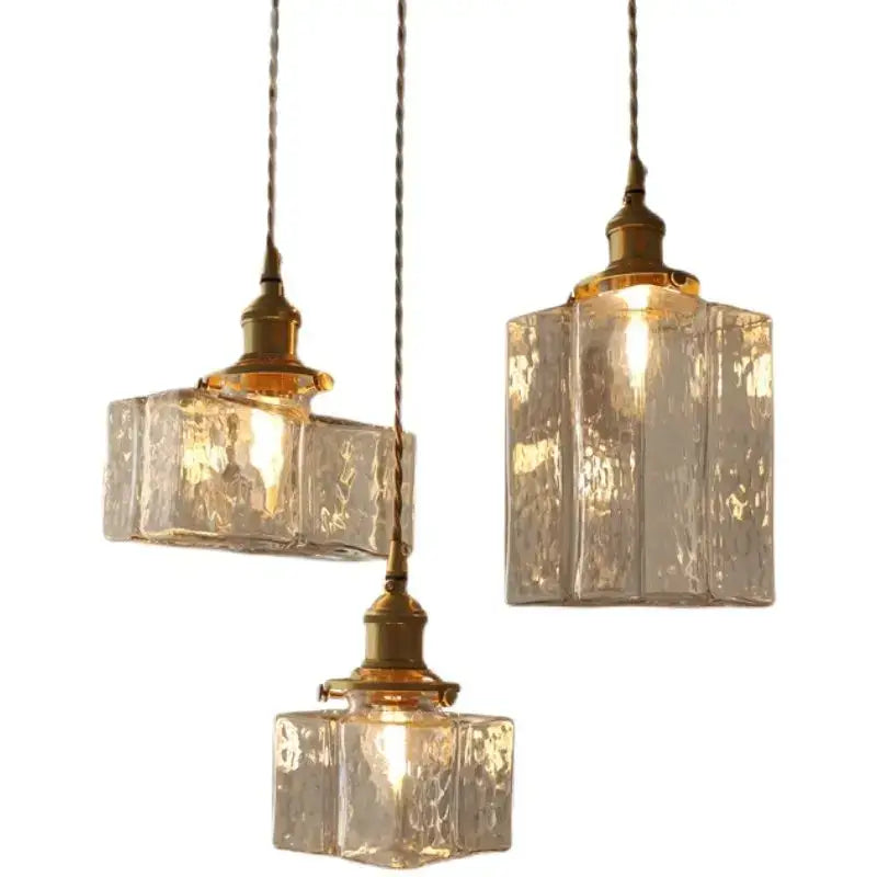 Three vintage amber glass pendant lights with textured shades and polished brass fixtures for dining room use