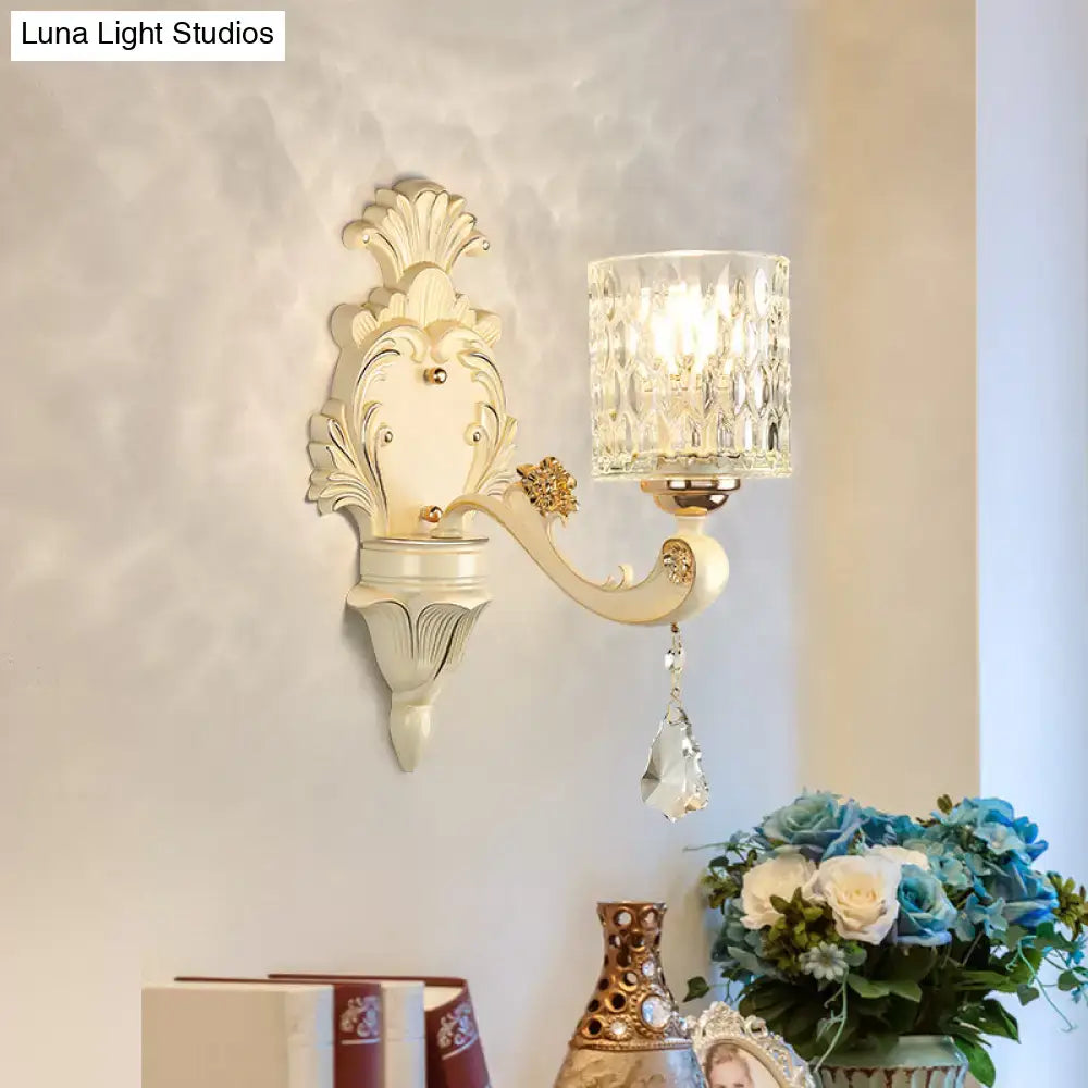 Antique cream-colored glass wall light with ornate scrollwork and faceted crystal shade for bedroom use