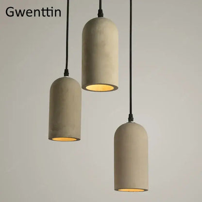 Three beige decorbites cement pendant lamps with black cords and warm yellow interiors for dining room lighting