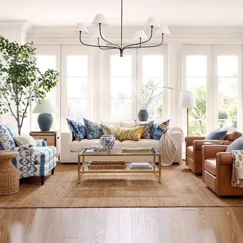 White sofa with blue and yellow patterned pillows under vintage black and gold iron finish cloth shade pendant light