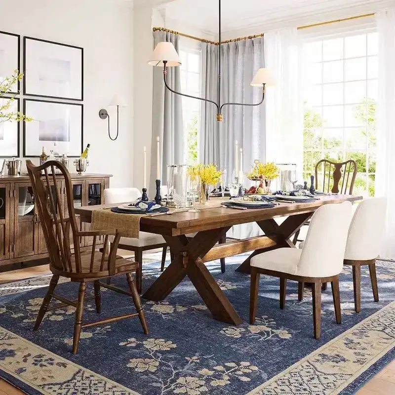 Rustic wooden dining table with x-shaped base and dark brown finish under vintage black and gold iron finish cloth shade pendant light