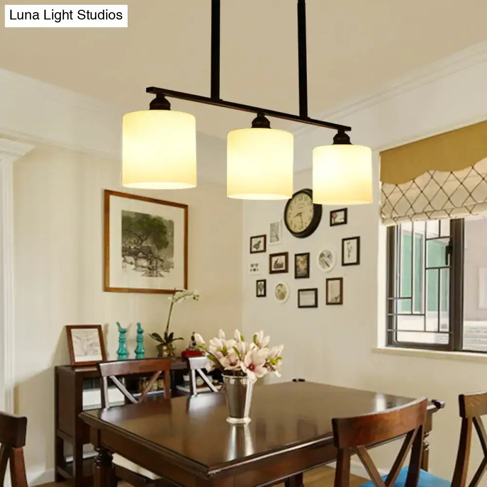 Vintage black metal chandelier with three off-white glass lampshades as a dining room island light pendant