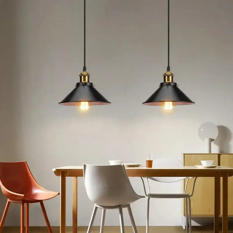 Vintage black metal pendant light with brass metal finish hanging above wooden dining table for kitchen island lighting