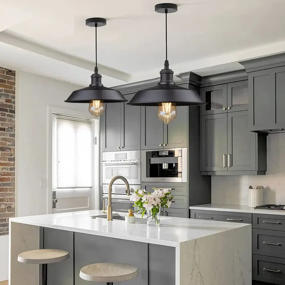Two black decorbites black farmhouse pendant lights with exposed filament bulbs hang above kitchen island