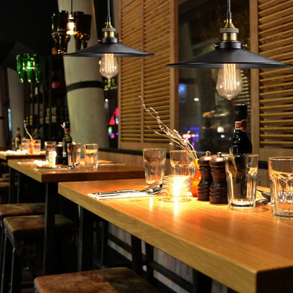 Industrial-style pendant light featuring vintage black iron finish with brass socket and edison bulb above wooden bar