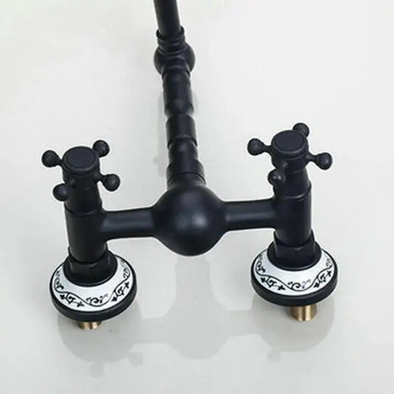 Vintage black swivel wall mounted bathroom faucet with black matte finish and ornate white ceramic bases featuring black scrollwork