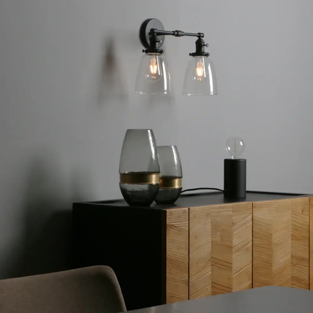 Industrial vintage black wall sconce with two clear glass shades and exposed filament bulbs for bedroom lighting