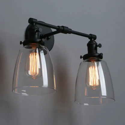 Vintage black two light wall sconce with industrial metal frame and clear glass shades for bedroom lighting