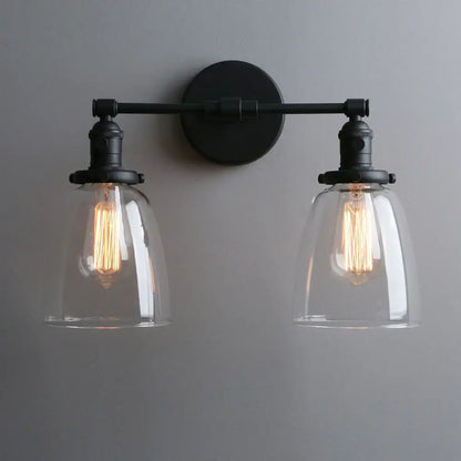 Vintage black wall sconce with two clear glass shades and exposed filament bulbs for bedroom lighting