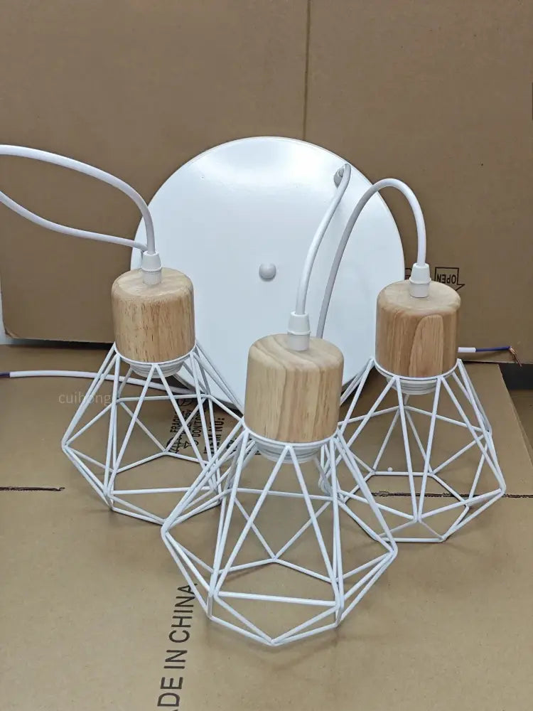Three white geometric wire pendant lights with natural wood caps complement vintage black wood and iron cage pendant light