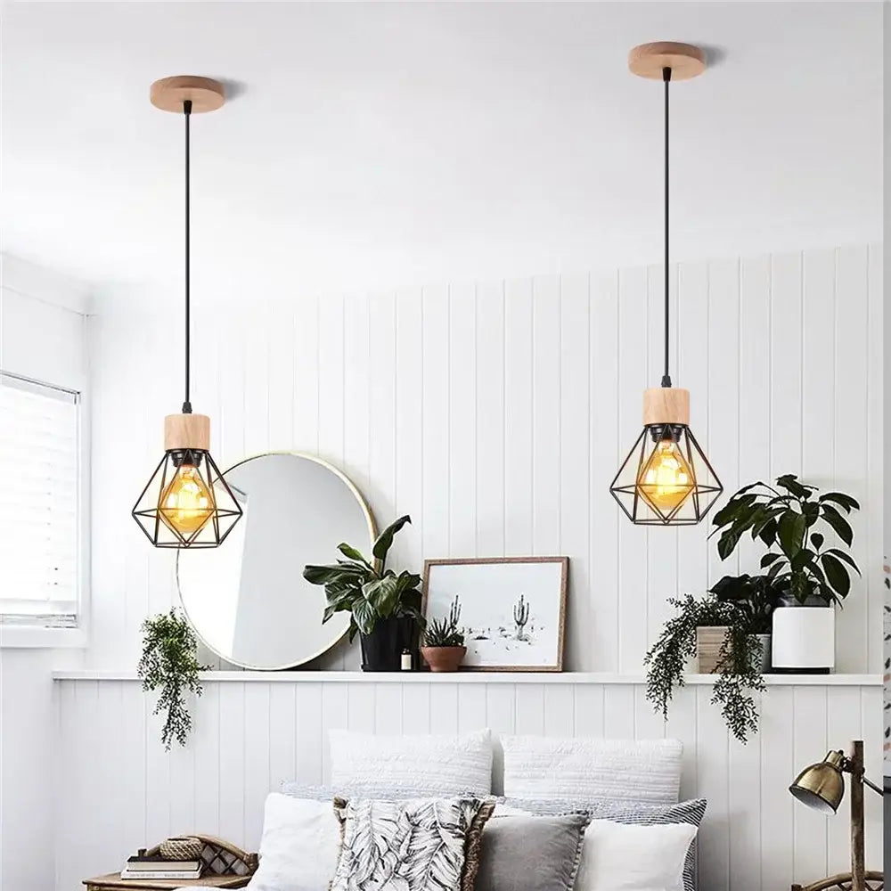 Two vintage black wood and iron cage pendant lights with amber bulbs hang for dining room lighting in small square meters