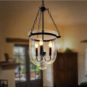 Vintage black wrought iron pendant lamp with clear glass enclosure and three lit candle-style bulbs for dining room decorbites black vintage