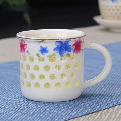 White ceramic tea cup with gold rim and colorful floral patterns above yellow perforated bowl from vintage cup set