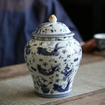 White porcelain general jar with intricate blue hand-painted fish floral patterns and golden finial for living room storage