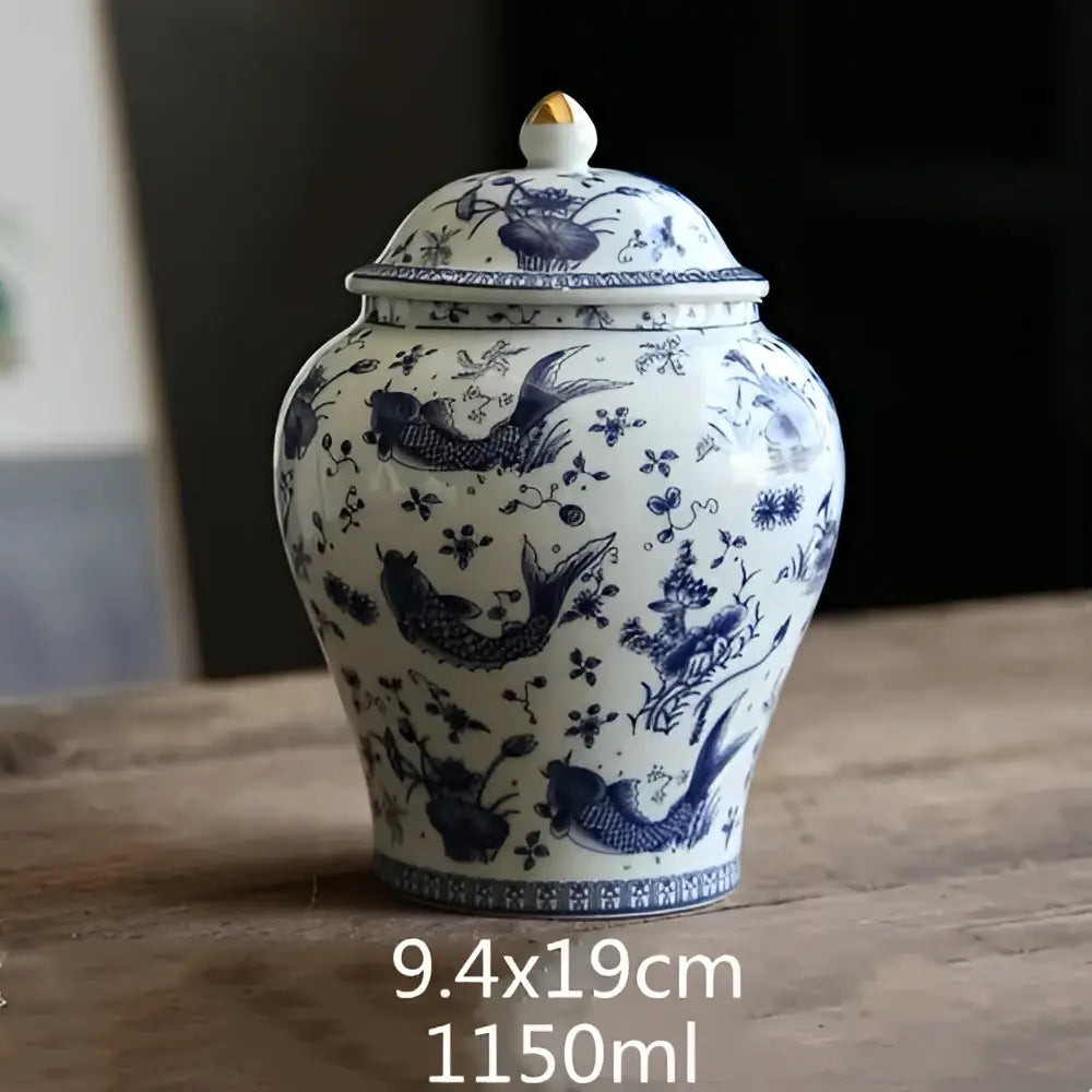 White porcelain general jar with intricate blue hand-painted fish and floral designs and golden finial lid decorbites blue