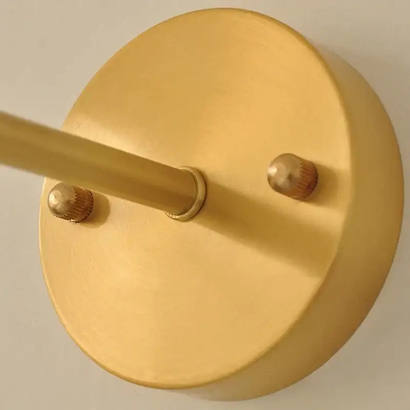 Vintage brass amber coffee glass wall sconce with gold-finished circular metal frame and decorative knurled knobs