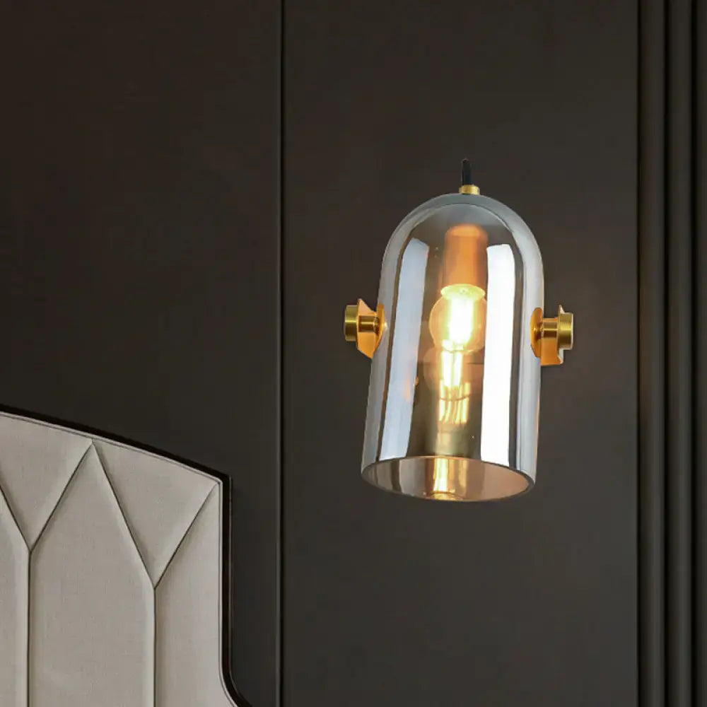 A vintage brass swivel shade cloche bedside sconce with amber and smoke glass dome for bedroom lighting