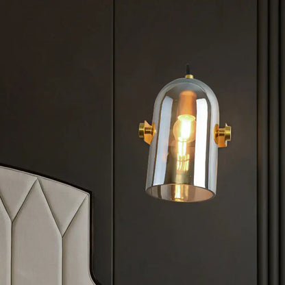 A vintage brass swivel shade cloche bedside sconce with amber and smoke glass dome for bedroom lighting