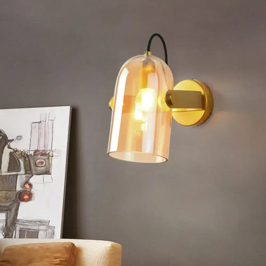 Warm amber glass bell-shaped swivel shade cloche bedside sconce with brass-finished metal base for bedroom use