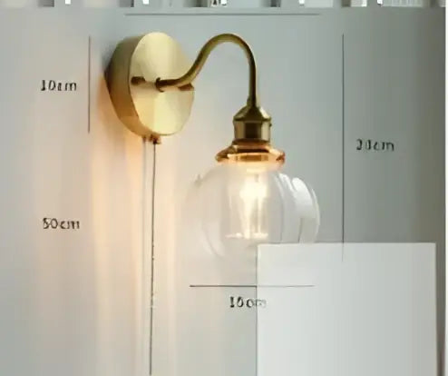 Vintage brass and amber glass led wall lamp with a brass-finished curved arm and clear glass bulb for bedroom sconce use