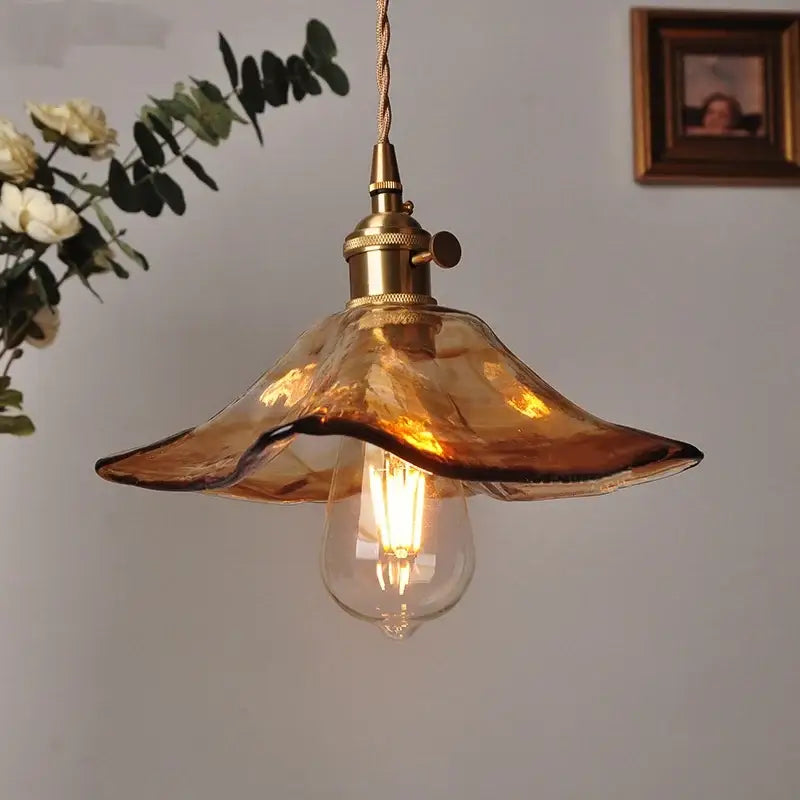 Vintage brass and amber glass pendant light featuring a warm amber glass pendant with brass fixture and exposed bulb