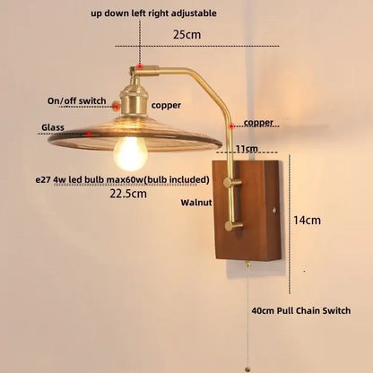 Copper-finished vintage brass wall sconce with amber glass shade, walnut mounting plate, and pull chain switch