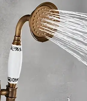 Vintage brass and bronze hand shower head faucet set with antique brass finish and white ceramic accents showing circular spray pattern