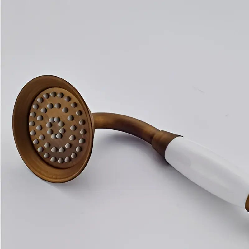 Antique brass hand shower head faucet set with white ceramic handle and circular spray face for bathroom use
