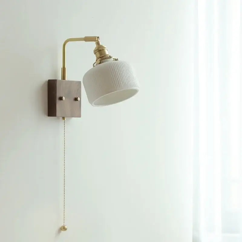 Vintage brass and ceramic led wall lights with a white ribbed ceramic lampshade and pull chain switch mounted on wood base